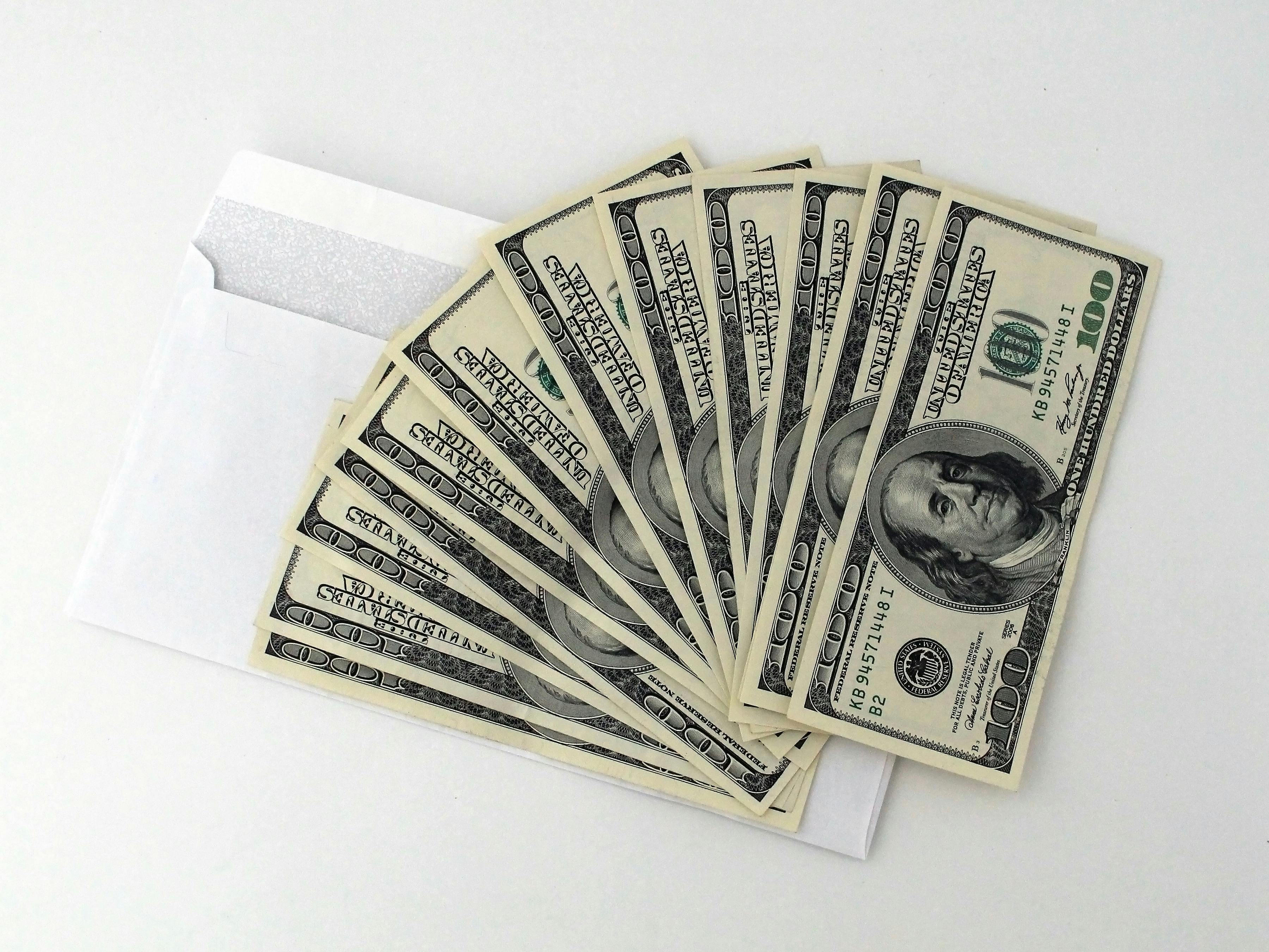 cash fanned out over a white envelope